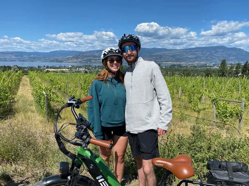 Couple on e-bikes checking smartphone navigation app during a self-guided Kelowna bicycle wine tour along the Okanagan wine trail