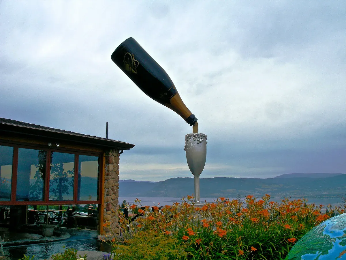 Giant bottle-and-glass sculpture outside Summerhill Pyramid Winery with Okanagan Lake behind, a Kelowna winery with a view reached by bike